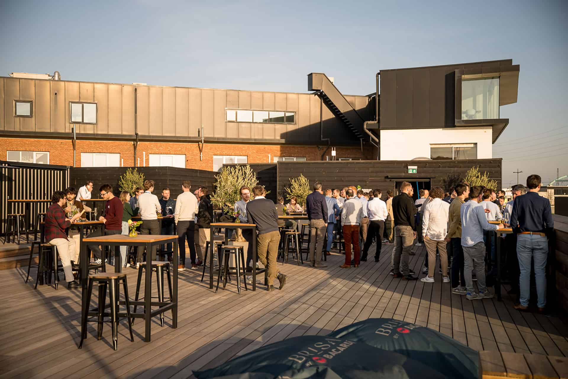 Gezellig terras met groep mensen op het dakterras van Brisa Antwerp, een trendy beachbar in Antwerpen voor een ontspannen sfeer en goede cocktails.